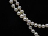 two strands of white pearls on a black mannequin necklace