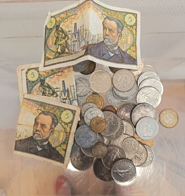 un récipient en verre rempli de pièces de monnaie et la photo du visage d'un homme