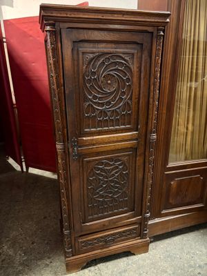 une armoire en bois ornée de sculptures, placée dans un coin de la pièce