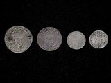 four silver coins are arranged in a row on a black surface