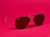 a pair of sunglasses sitting on top of a pink surface