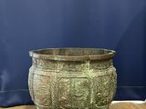 an old bronze pot sitting on top of a wooden floor next to a blue curtain