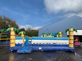 un grand toboggan aquatique gonflable orné de palmiers sur le dessus
