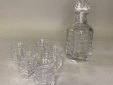 une carafe en verre et des verres posés sur une table