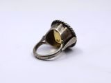 a close up of a silver ring with a yellow stone in it