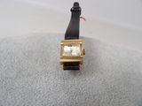 une montre en or avec un bracelet noir sur un fond blanc