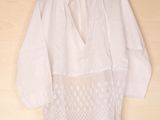 a white blouse hanging on a hanger on a wooden wall