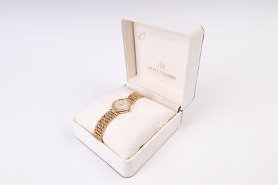 une boîte blanche contenant une montre, posée sur une surface blanche