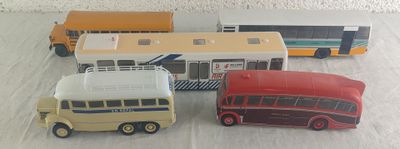 quatre petits bus posés sur une surface blanche