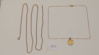 deux colliers en or et une pièce d'or posés sur une surface blanche