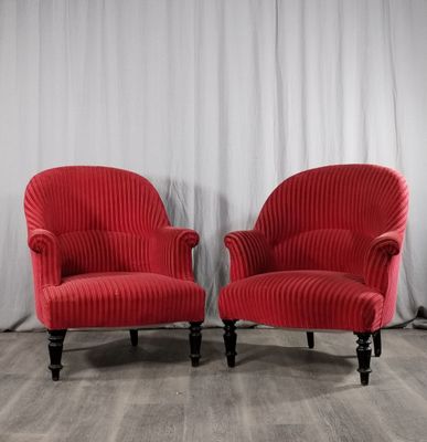 une paire de fauteuils rembourrés rouges devant un rideau blanc