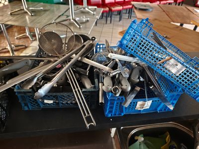 un tas d'ustensiles de cuisine dans un panier bleu posé sur une table