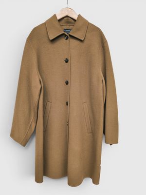 Ce manteau est en laine et comporte des boutons au niveau du col.