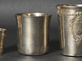 trois tasses en argent et une cuillère posées sur une table