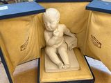 une petite statue représentant un bébé assis à l'intérieur d'une boîte