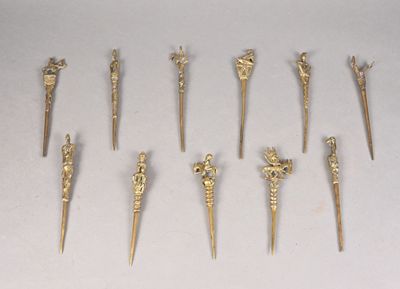 plusieurs objets métalliques de couleur dorée, de formes variées, posés sur une surface blanche