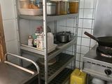 une étagère métallique avec des casseroles et des poêles dans une cuisine