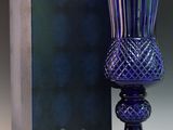 un vase en verre violet posé à côté d'une boîte bleue sur une surface blanche