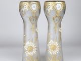 pair of silver vases with gold and white designs on them