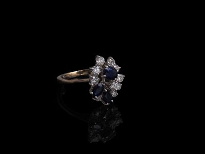 un gros plan d'une bague sertie d'un diamant et d'un saphir sur une surface noire