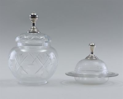 two clear glass jars with silver lids and lids on a table