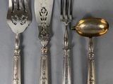 four forks and a spoon on a table with a spoon in the middle