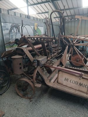 a pile of junk in a garage with a tractor in the background