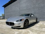 a silver sports car parked in front of a brick wall