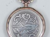 a silver pocket watch with a bird on it