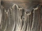 a close up of a silver vase with a bird on it