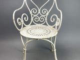 an old white iron chair with a heart design on the back