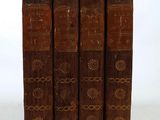 three old books are stacked on top of each other on a white surface