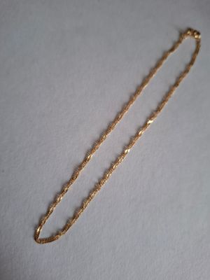 a close up of a gold chain on a white surface