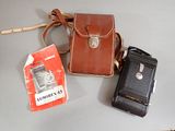 two old cell phones and a leather case on a table