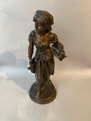 bronze figurine of a girl holding a basket of flowers