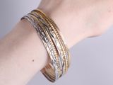two tone gold and silver bang bracelets on a woman ' s arm