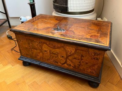 un coffre en bois posé sur un parquet en bois massif, à côté d'un radiateur