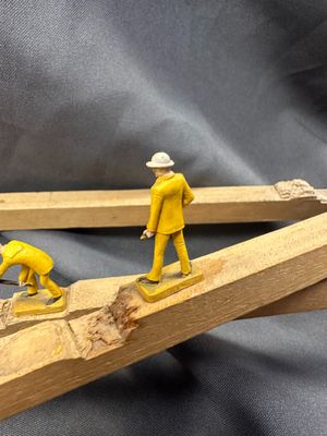 two figurines of men working on a piece of wood