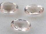 trois pierres précieuses de topaze blanche taillées en ovale, posées sur une surface blanche