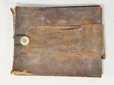 an old book with a button on it on a white surface