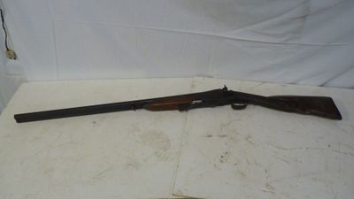 un vieux fusil avec une poignée en bois sur une surface blanche