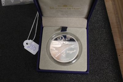 une pièce d'argent dans une boîte violette sur laquelle est accrochée une étiquette