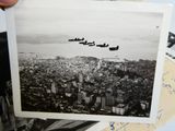 a black and white photo of a group of planes flying over a city