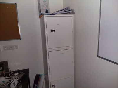a white refrigerator next to a white cabinet in a room