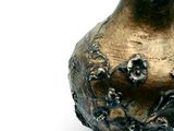a bronze vase that is sitting on a white surface