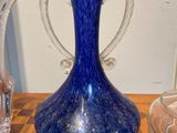 a blue glass vase sitting on a table next to a glass vase