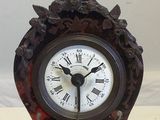 a small clock with a statue on top of it