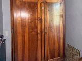 a wooden cabinet in the corner of a room next to a chair