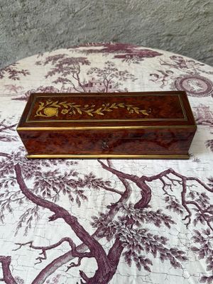 une boîte en bois posée sur un lit recouvert d'une couverture violette et blanche