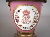a pink vase with a crown on it sitting on a stand